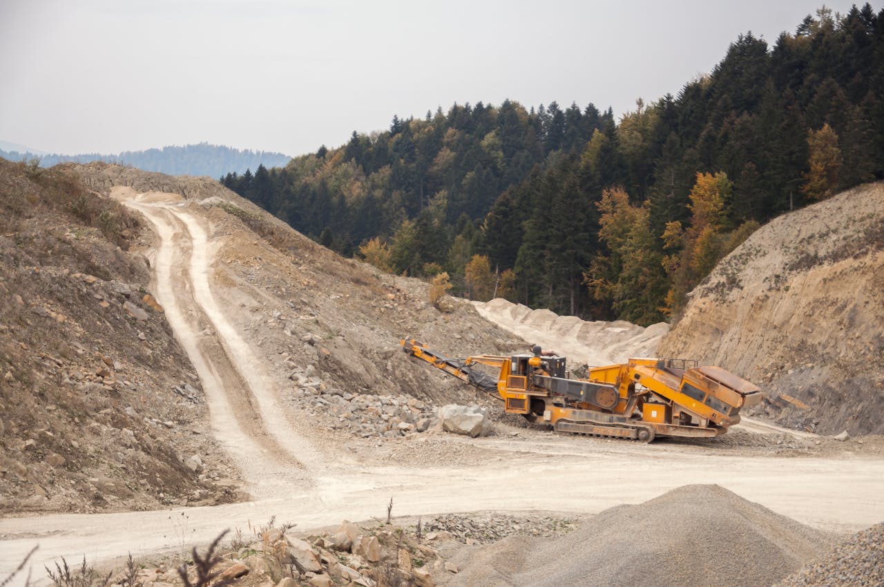 Industrial machinery operating in a forest quarry landscape during daytime.
